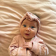 Delilah is registered to the contest to win money with this photo: baby, infant, pink_clothing, headband, blue_eyes, lying_down, blanket, cute, portrait, child, soft_texture, newborn, expression, hands, indoor, cozy, small_hands, face, looking_up, adorable