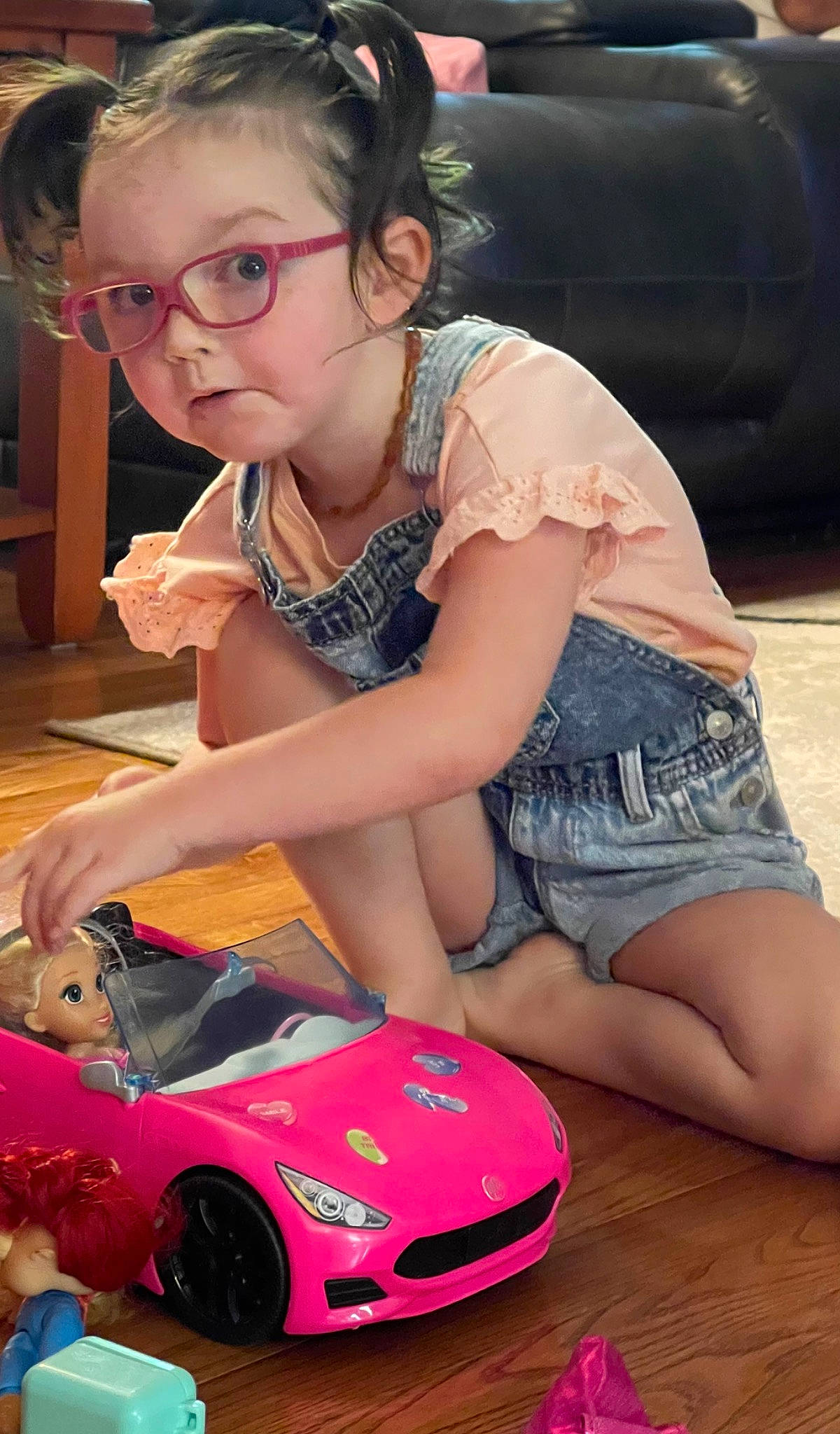 Raven is registered to the contest to win money with this photo: automotive_design, automotive_lighting, automotive_wheel_system, bumper, car, child, event, fun, hood, human_leg, motor_vehicle, person, photograph, pink, shorts, snapshot, thigh, tire, toy, vehicle