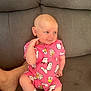 Margot is registered to the contest to win money with this photo: baby, child, clothing, couch, cute, foot, gray_couch, hand_on_face, hello_kitty, indoor, infant, looking_sideways, person, pink_onesie, portrait, sitting, smiling, sock, white_sock, young_child