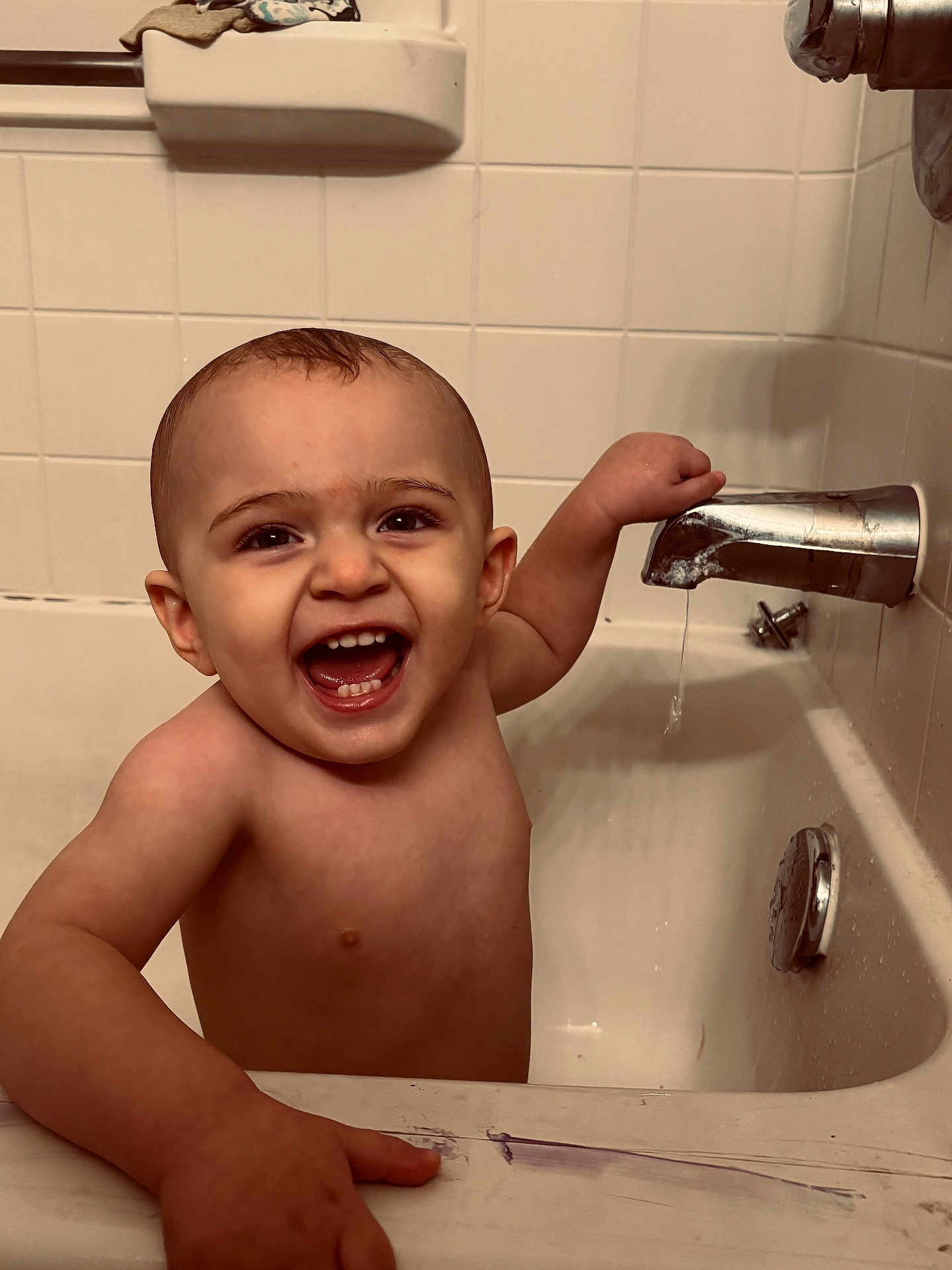 Oliver is registered to the contest to win money with this photo: baby, bathtub, bathroom, child, faucet, smiling, water, tiles, happy, tub, skin, hand, face, mouth, teeth, head, arm, indoor, person, cleaning