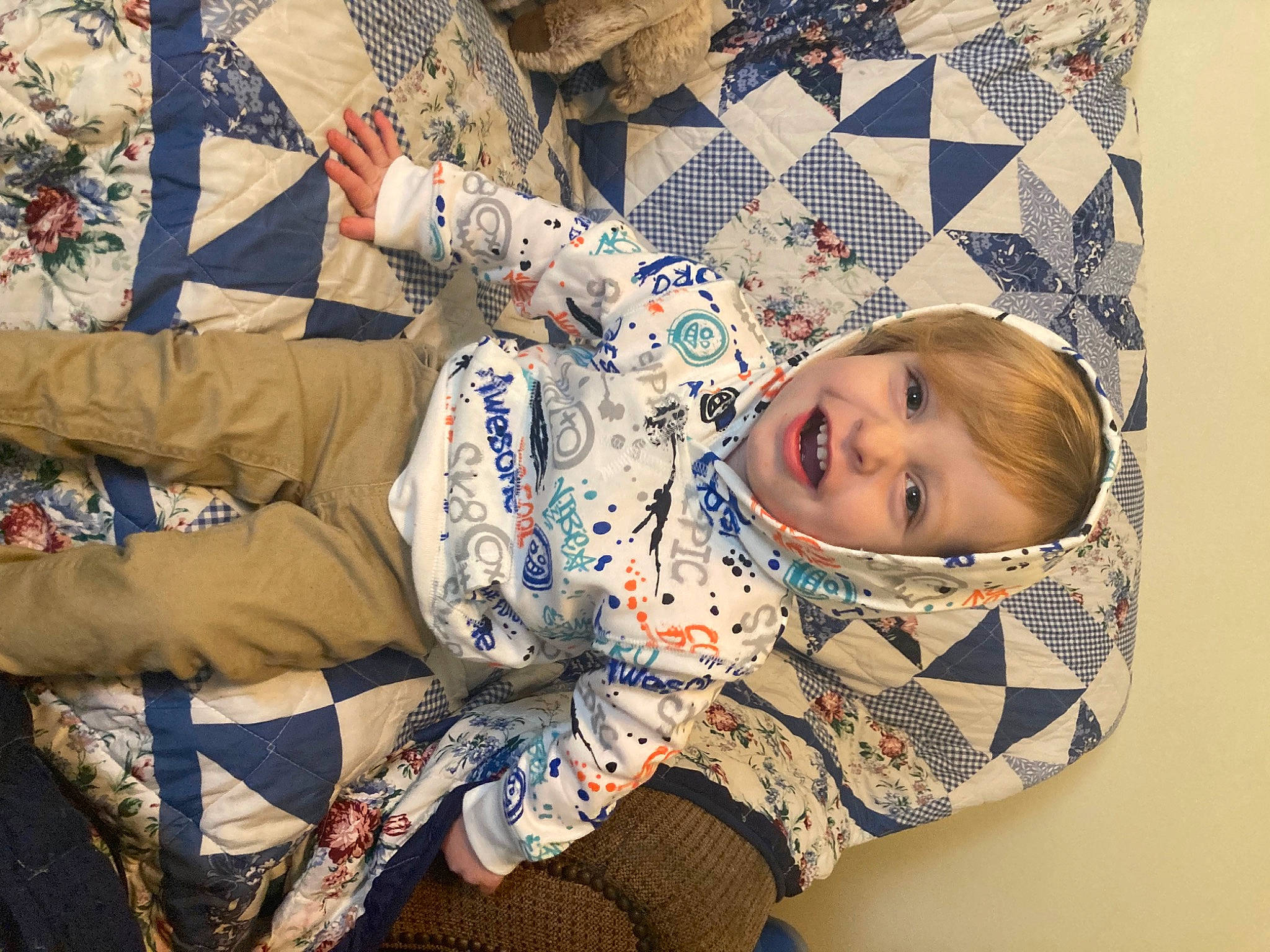 Kyren is registered to the contest to win money with this photo: baby, baby_toddler_clothing, child, comfort, facial_expression, flooring, fun, happy, joy, linens, military_camouflage, pattern, person, room, sitting, sleeve, smile, textile, thigh, toddler