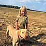 blond_hair, child, clouds, collar, dirt, dog, field, harvested_field, labrador, leash, outdoors, rural, shadow, sky, smile, standing, sunlight, training_toy, trees, tshirt