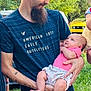 man, baby, child, outdoor, greenery, beard, casual_clothing, holding, infant, nature, portrait, grass, car, tattoo, short_sleeves, jeans, summer, family, daylight, toddler