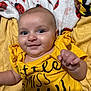 baby, smile, yellow_shirt, blanket, ladybug_pattern, infant, child, cute, happy, portrait, face, skin, hand, lying_down, soft_texture, comfortable, eyes, head, clothing, indoors