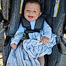 baby, child, car_seat, blanket, smiling, blue_eyes, white_clothing, happy, outdoor, seatbelt, infant, person, cute, comfort, portrait, holding, fabric, sitting, toy, daylight
