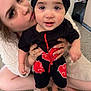 child, adult, baby, turban, black_clothing, red_pattern, indoor, carpet, affection, kiss, person, holding, closeup, cute, family, love, casual, home, portrait, smile