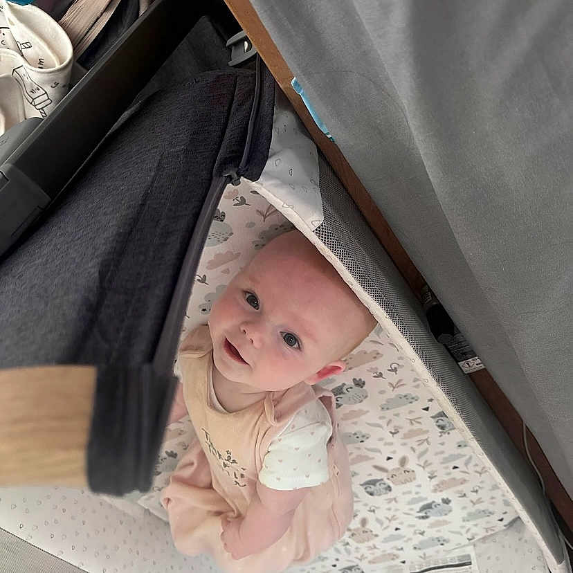 Autumn Bolding joined the competition — help win amazing prizes! baby, child, crib, curious, cute, face, floor, home, indoors, infant, looking_up, newborn, patterned_bedding, person, pink_clothing, playpen, smiling, soft_fabric, white_shirt, young_child