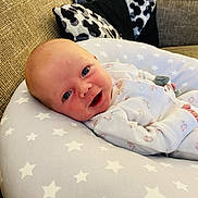 Autumn Bolding is registered to the contest to win money with this photo: baby, infant, smiling, cushion, star_pattern, pillow, sofa, indoor, face, clothing, sleepwear, cute, child, newborn, resting, comfort, happy, portrait, home, relaxing
