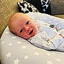 baby, infant, smiling, cushion, star_pattern, pillow, sofa, indoor, face, clothing, sleepwear, cute, child, newborn, resting, comfort, happy, portrait, home, relaxing