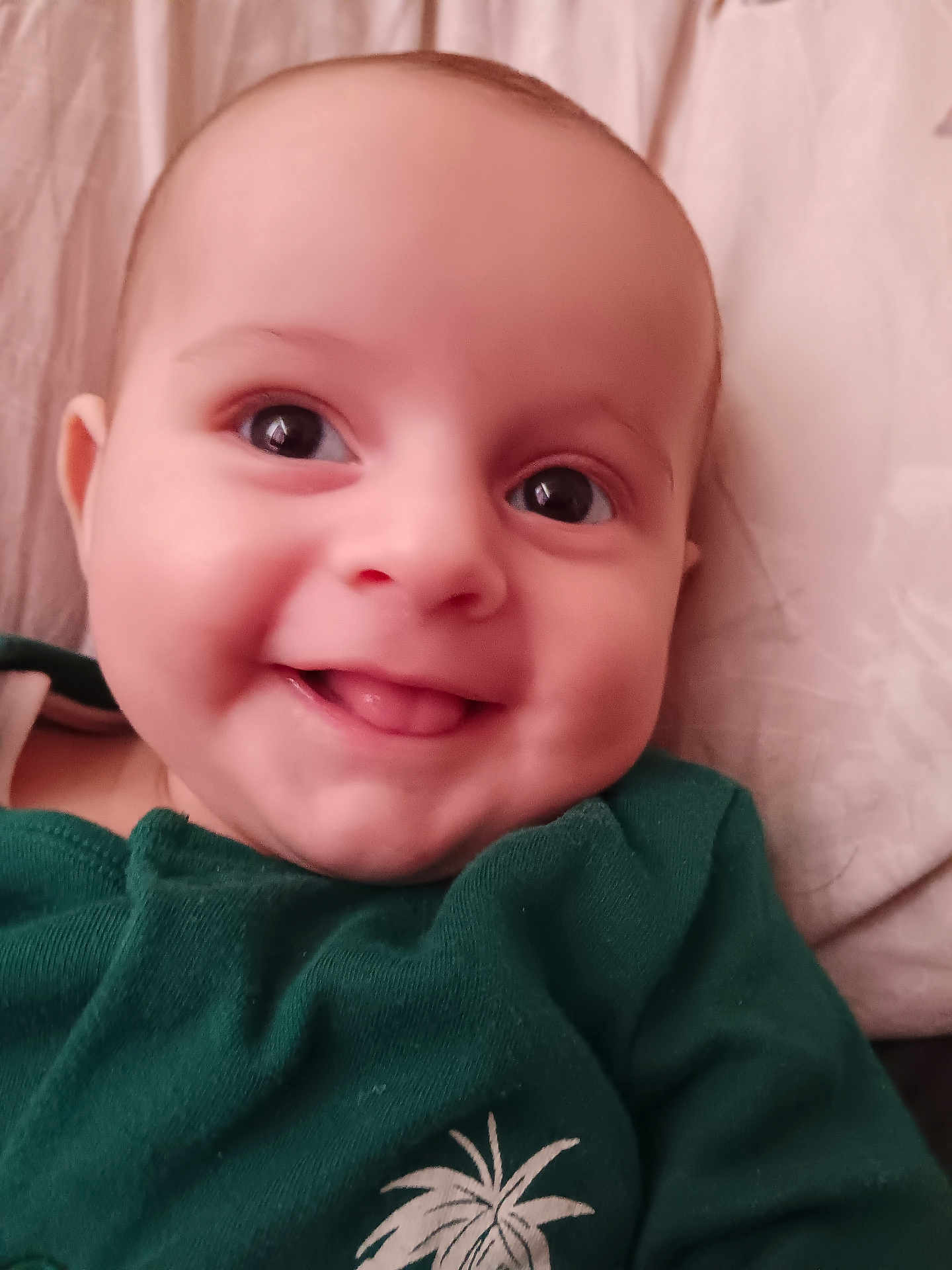 Finlay joined the competition — help win amazing prizes! baby, smiling, face, tongue, green_clothing, infant, close_up, cute, person, child, skin, eyes, head, apparel, portrait, lying_down, indoors, soft_lighting, expression, young
