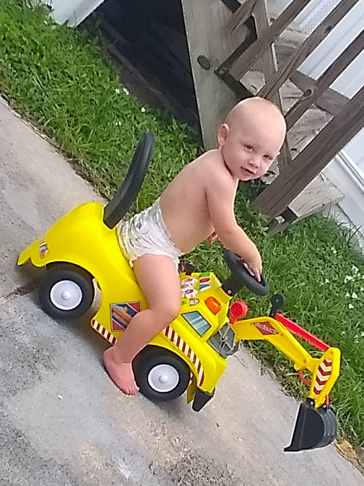 Alexzander is registered to the contest to win money with this photo: car, child, grass, lawn, leg, outdoor_power_equipment, person, plant, play, riding_toy, toddler, toy, vehicle, yellow