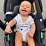 baby, car_seat, onesie, smiling, happy, infant, child, baby_clothing, seatbelt, black, white, cute, young_child, laughing, person, infant_seat, outdoor, face, human, joy