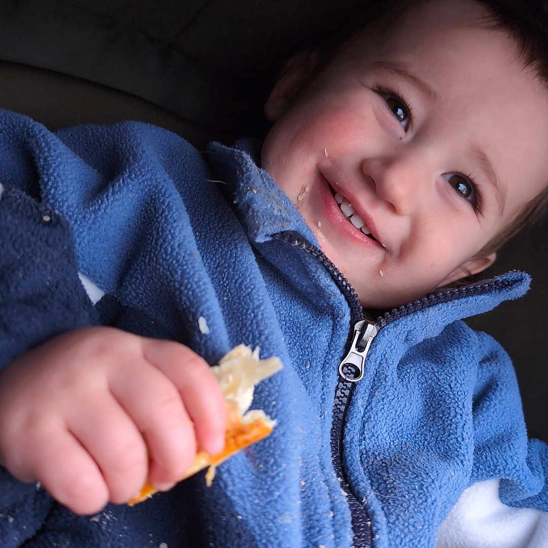 Kelson joined the competition — help win amazing prizes! baby, bodypart, bread, clothing, coat, eating, face, finger, food, hand, head, hood, hoodie, jacket, knitwear, person, photography, portrait, sweater, sweatshirt