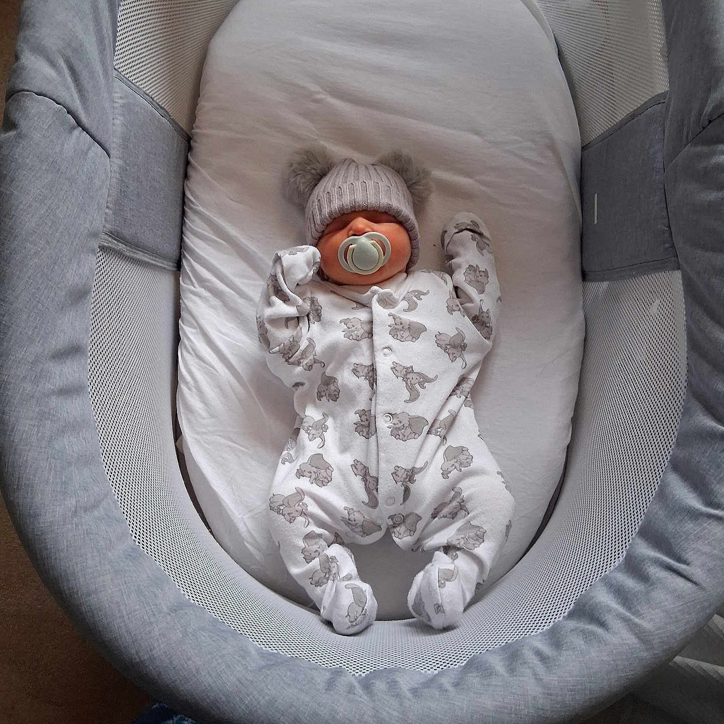 Oaklynn-Ayla is registered to the contest to win money with this photo: baby, bassinet, bed, child, clothing, cozy, cute, gray, hat, indoor, infant, mesh, newborn, onesie, pacifier, pom_poms, resting, sleeping, soft, white