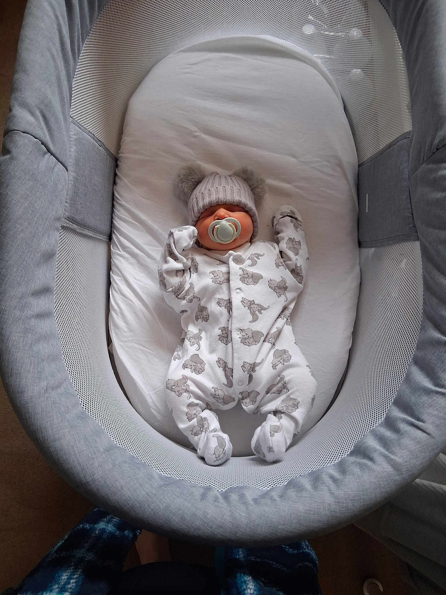 Oaklynn-Ayla is registered to the contest to win money with this photo: baby, bassinet, bed, child, clothing, cozy, cute, gray, hat, indoor, infant, mesh, newborn, onesie, pacifier, pom_poms, resting, sleeping, soft, white