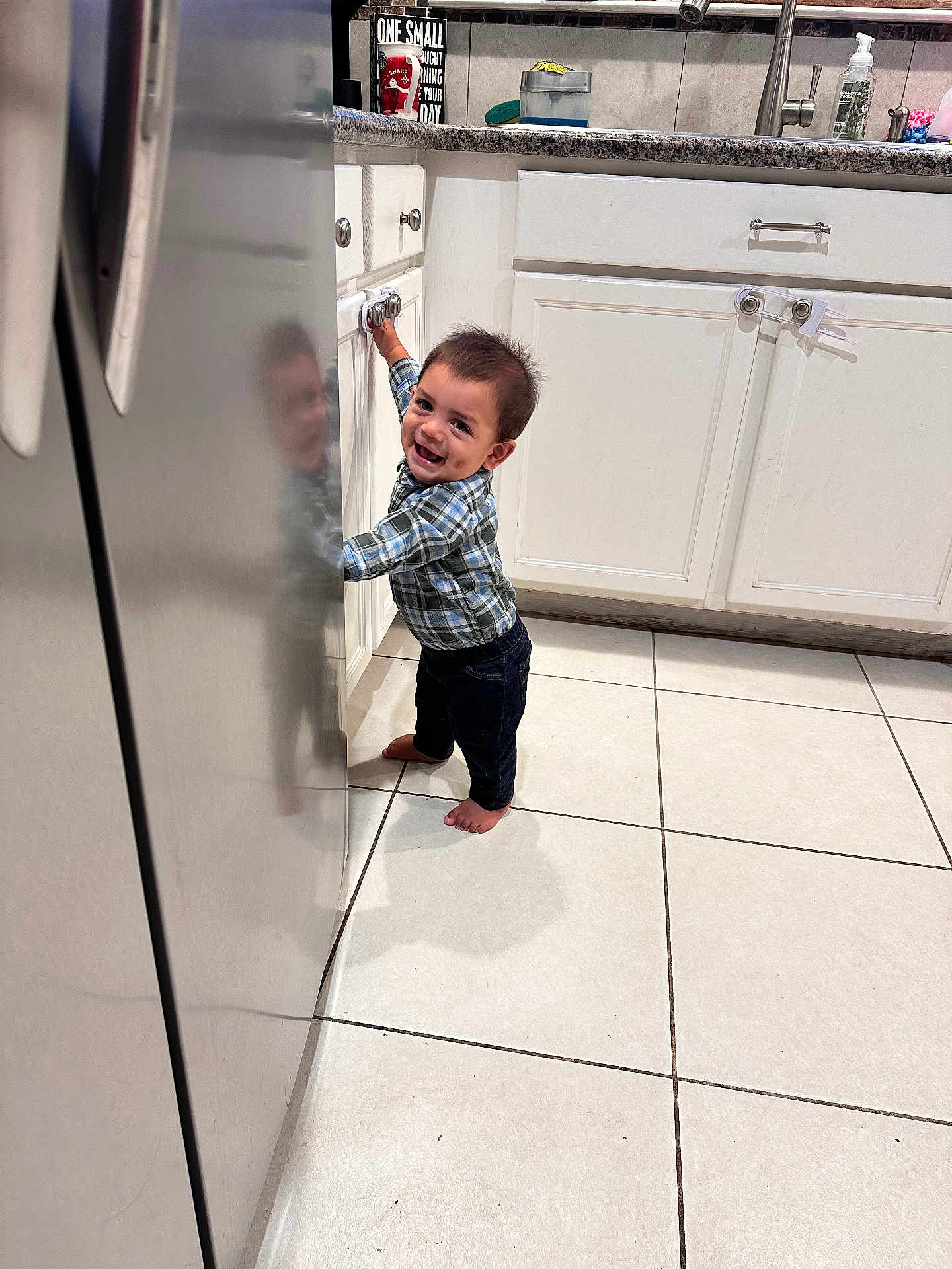 Lorenzo joined the competition — help win amazing prizes! toddler, child, smiling, barefoot, kitchen, cabinet, refrigerator, reflection, tile_floor, plaid_shirt, jeans, person, indoor, home, happy, young_child, curly_hair, standing, domestic, casual_clothing