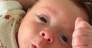 Griffin is registered to the contest to win money with this photo: arm, baby, background, closeup, clothing, curious, cute, expression, face, hand, indoor, infant, lying_down, newborn, person, portrait, pout, skin, soft, wide_eyes