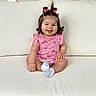 baby, child, smiling, sitting, couch, pink_bows, short_sleeves, watermelon_print, socks, indoor, cute, happy, person, portrait, hair_bows, infant, plaid, furniture, skin, face