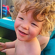 Jared Blodgett is registered to the contest to win money with this photo: child, smiling, blonde_hair, curly_hair, outdoor, sunlight, play_area, plastic_chair, cushion, bare_chest, happy, closeup, person, grass, furniture, daylight, skin, young, portrait, play