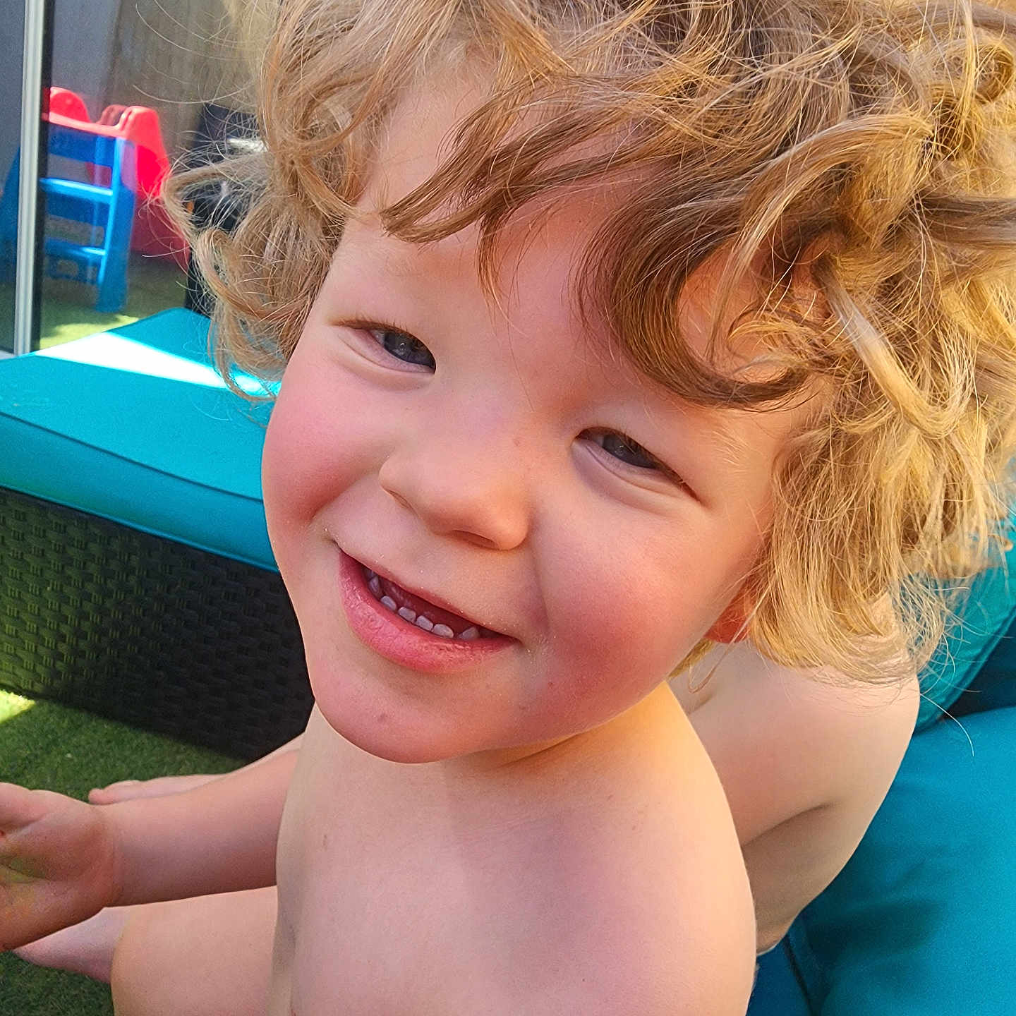 Jared Blodgett is registered to the contest to win money with this photo: bare_chest, blonde_hair, child, closeup, curly_hair, cushion, daylight, furniture, grass, happy, outdoor, person, plastic_chair, play, play_area, portrait, skin, smiling, sunlight, young