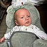 Teddy is registered to the contest to win money with this photo: baby, infant, child, baby_seat, plush, green, face, looking, white_clothing, floral_pattern, indoors, comfort, seatbelt, head_support, newborn, person, young_child, portrait, resting, soft_texture