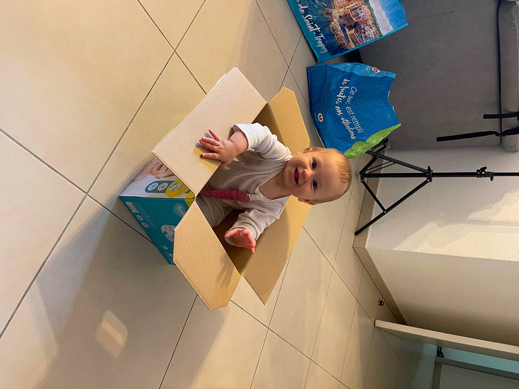 Romy a rejoint le concours — aidez-le/la à gagner de superbes lots ! art, baby, cardboard, carton, ceiling, child, floor, flooring, fun, joy, material_property, paper, paper_product, person, play, room, smile, space, t_shirt, toddler