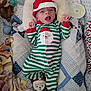 baby, infant, christmas_pajamas, santa_hat, blanket, quilt, stuffed_toy, pacifier, bed, face, sleepwear, holiday, cute, child, lying_down, soft_toys, cozy, expression, indoor, newborn