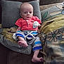 baby, blanket, clothing, couch, cozy, cute, expression, face, foot, furniture, hand, indoor, infant, medical_tube, person, pillow, portrait, red_shirt, sitting, striped_pants