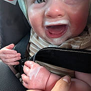 Adam is registered to the contest to win money with this photo: baby, car_seat, child, closeup, clothing, cute, expression, feet, hands, happy, holding, indoors, infant, milk_mustache, no_smoking_sign, person, seatbelt, skin, smiling, straps