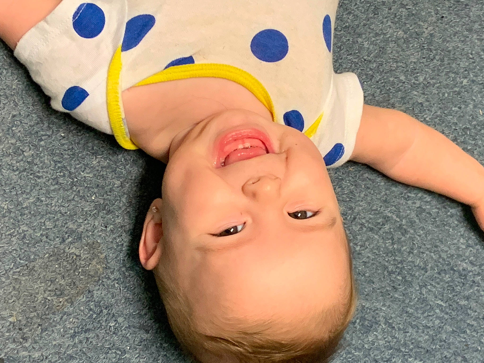 Emersyn is registered to the contest to win money with this photo: baby_toddler_clothing, carmine, cheek, child, eye, flooring, foot, fun, gesture, happy, jaw, leisure, mammal, mouth, nose, people_in_nature, person, smile, thumb, toddler