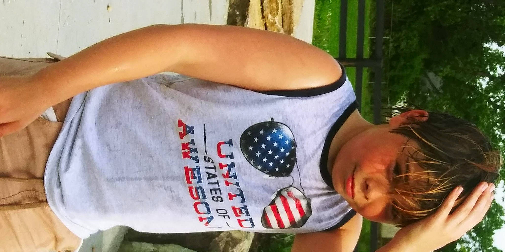 Cameron is registered to the contest to win money with this photo: abdomen, arm, cap, chest, elbow, flag, fun, grass, hat, human_leg, leisure, person, physical_fitness, plant, recreation, sun_hat, t_shirt, thigh, tree, trunk