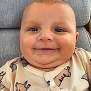 Camille participe au concours pour gagner de l'argent avec cette photo : baby, child, smile, face, onesie, animal_print, couch, gray_cushion, happy, infant, cute, closeup, portrait, indoor, soft_lighting, skin, head, eyes, mouth, buttoned_clothing