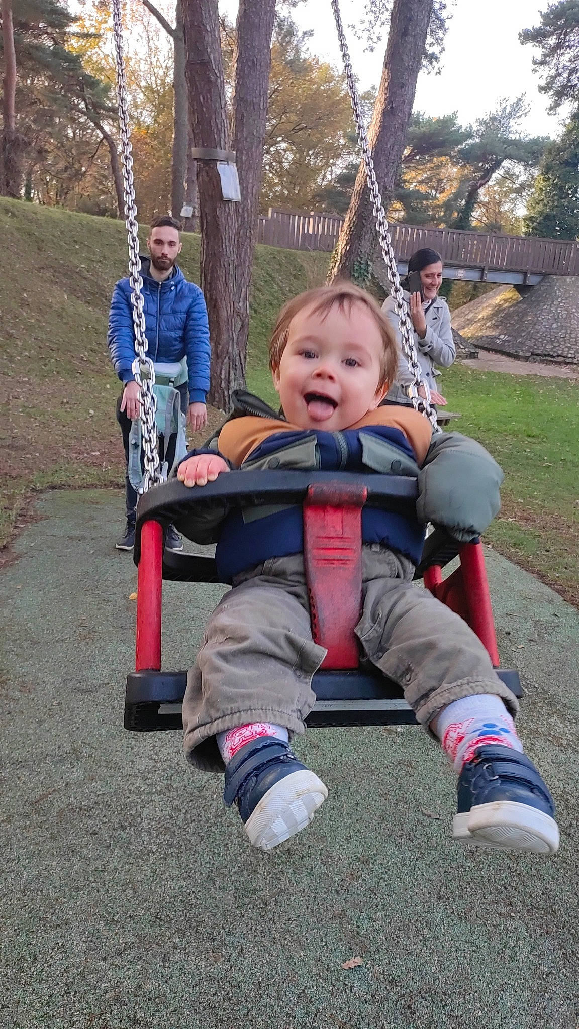 Aylan participe au concours pour gagner de l'argent avec cette photo : baby, baby_toddler_clothing, child, city, fun, grass, happy, jacket, joy, leisure, outdoor_play_equipment, person, plant, play, playground, public_space, recreation, sitting, smile, swing