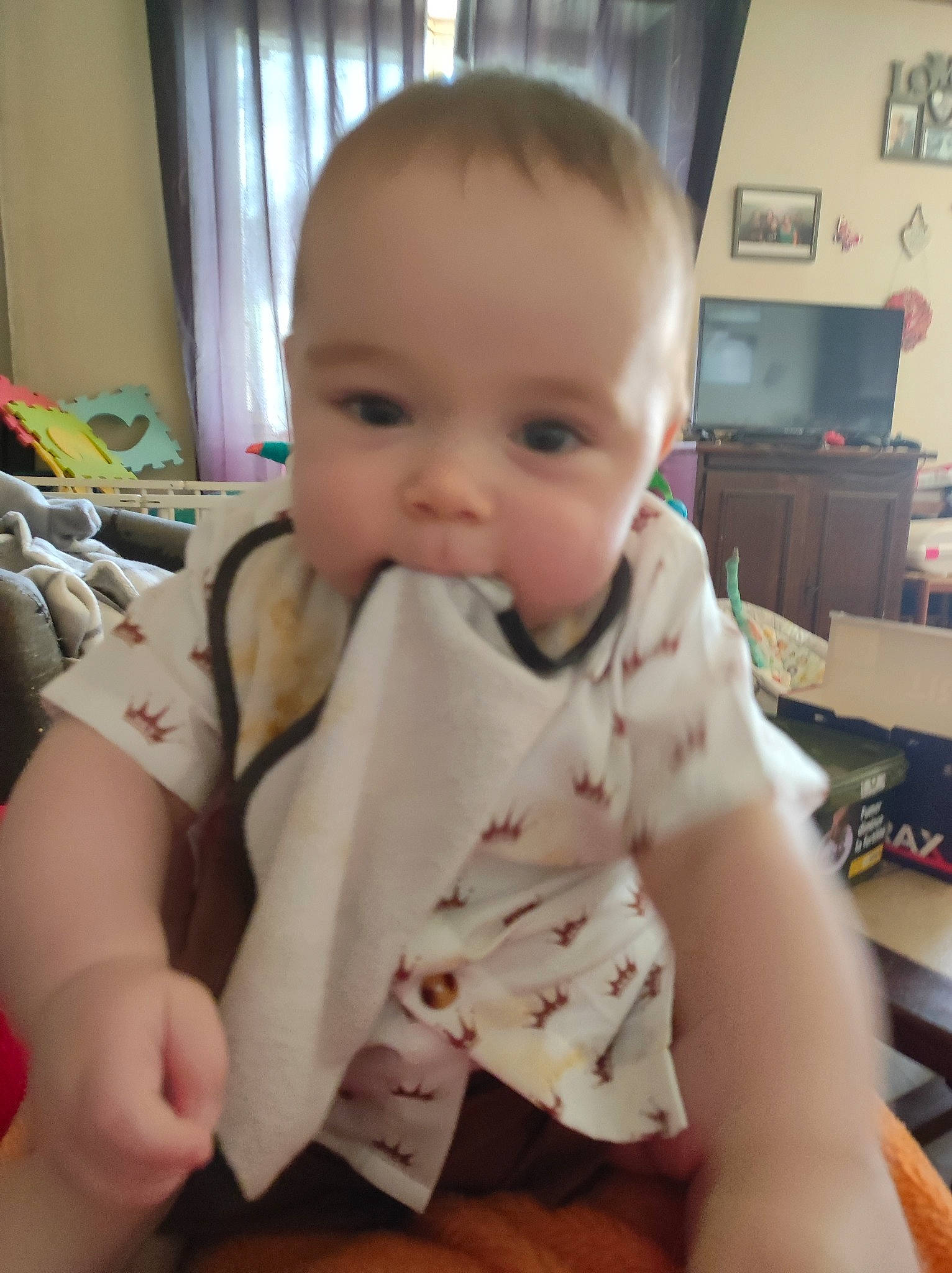 Aylan participe au concours pour gagner de l'argent avec cette photo : baby, baby_toddler_clothing, cheek, chest, child, comfort, curtain, flooring, fun, pattern, person, room, sitting, skin, sleeve, thumb, toddler, wood