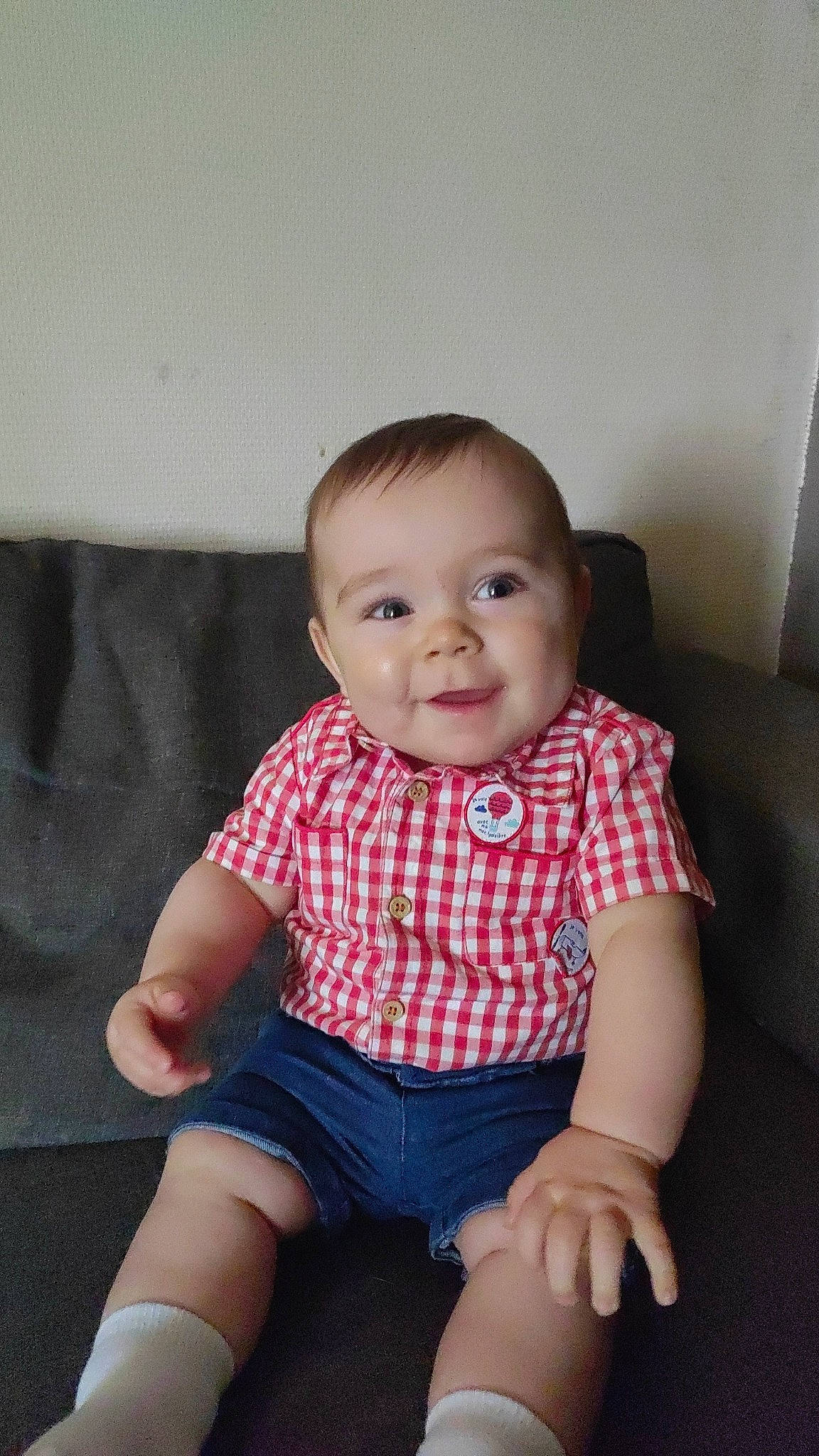 Aylan participe au concours pour gagner de l'argent avec cette photo : baby, baby_toddler_clothing, cheek, clothing, comfort, finger, happy, human_body, human_leg, iris, joy, knee, pattern, person, shorts, sitting, skin, sleeve, smile, t_shirt