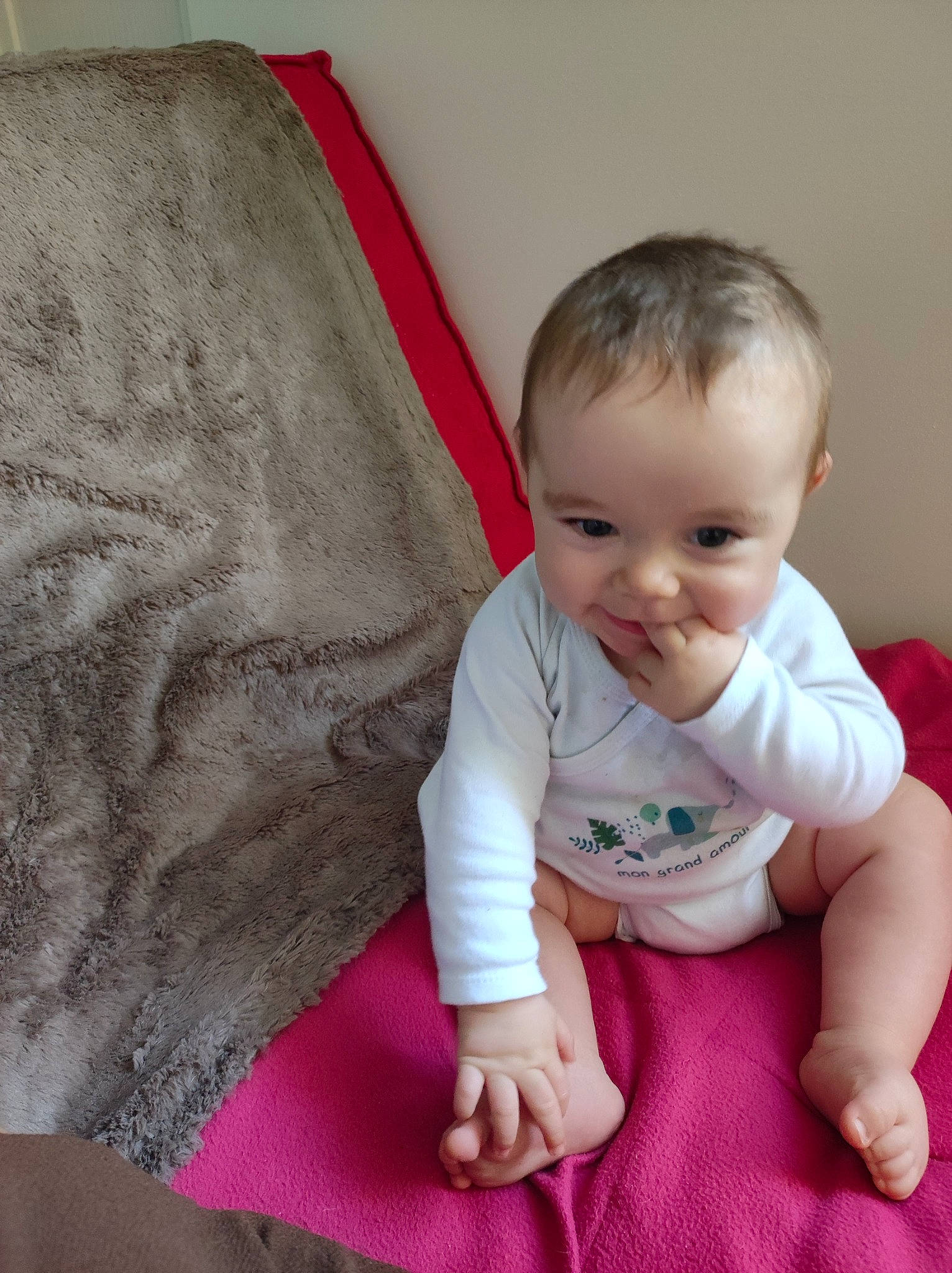 Aylan participe au concours pour gagner de l'argent avec cette photo : baby, baby_toddler_clothing, barefoot, cheek, child, chin, comfort, couch, finger, flooring, happy, linens, person, sitting, skin, sleeve, smile, t_shirt, thumb, toddler