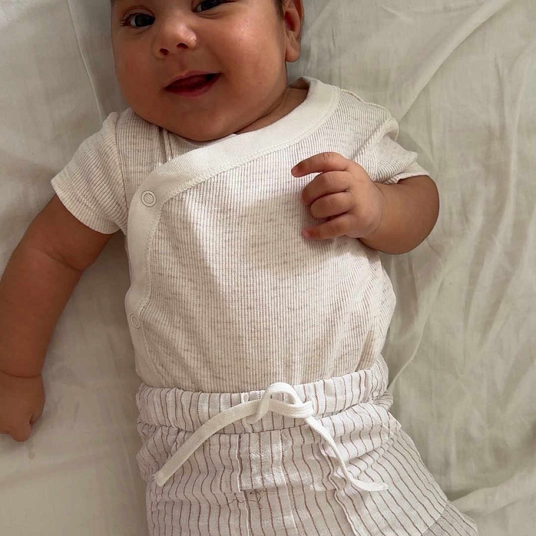 Maheidine participe au concours pour gagner de l'argent avec cette photo : baby, bed, child, cute, face, foot, hand, happy, indoors, infant, lying_down, person, portrait, resting, sleepwear, smiling, soft_light, striped_pants, white_clothing, young