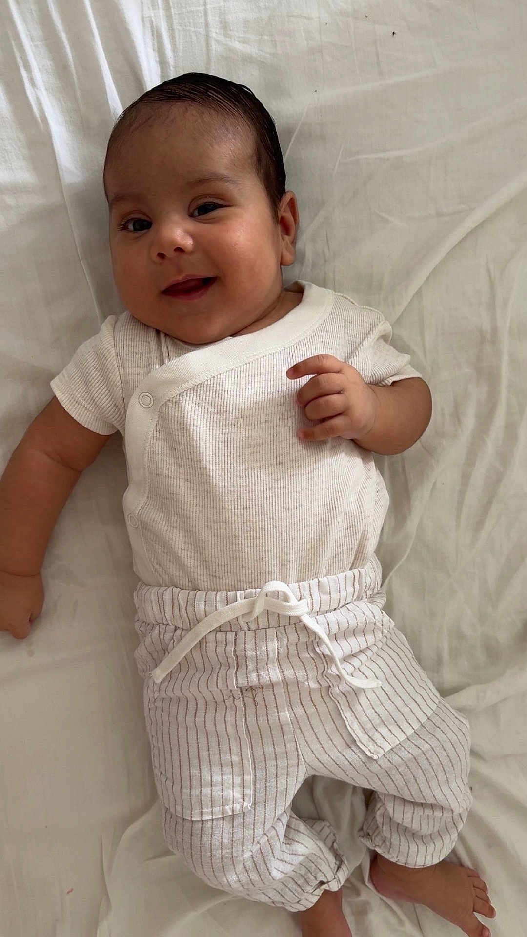 Maheidine participe au concours pour gagner de l'argent avec cette photo : baby, child, smiling, white_clothing, striped_pants, lying_down, bed, infant, cute, happy, person, foot, hand, face, soft_light, indoors, portrait, resting, young, sleepwear