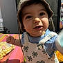 baby, child, clothing, colorful, curious, cute, eyes, face, hand, hat, indoor, infant, palm_tree_pattern, person, portrait, romper, sitting, smiling, snacks, table
