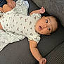 Aaliyah joined the competition — help win amazing prizes! baby, infant, onesie, floral_pattern, couch, gray_couch, blanket, curious, wide_eyes, open_mouth, hand, foot, person, indoor, child, soft_fabric, resting, casual_clothing, cute, portrait