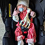 baby, infant, car_seat, pacifier, hat, toy, giraffe_toy, striped_clothing, white_socks, cute, child, indoors, seatbelt, hand_gesture, newborn, smiling, cuddly, soft_toy, red_clothing, black_car_seat
