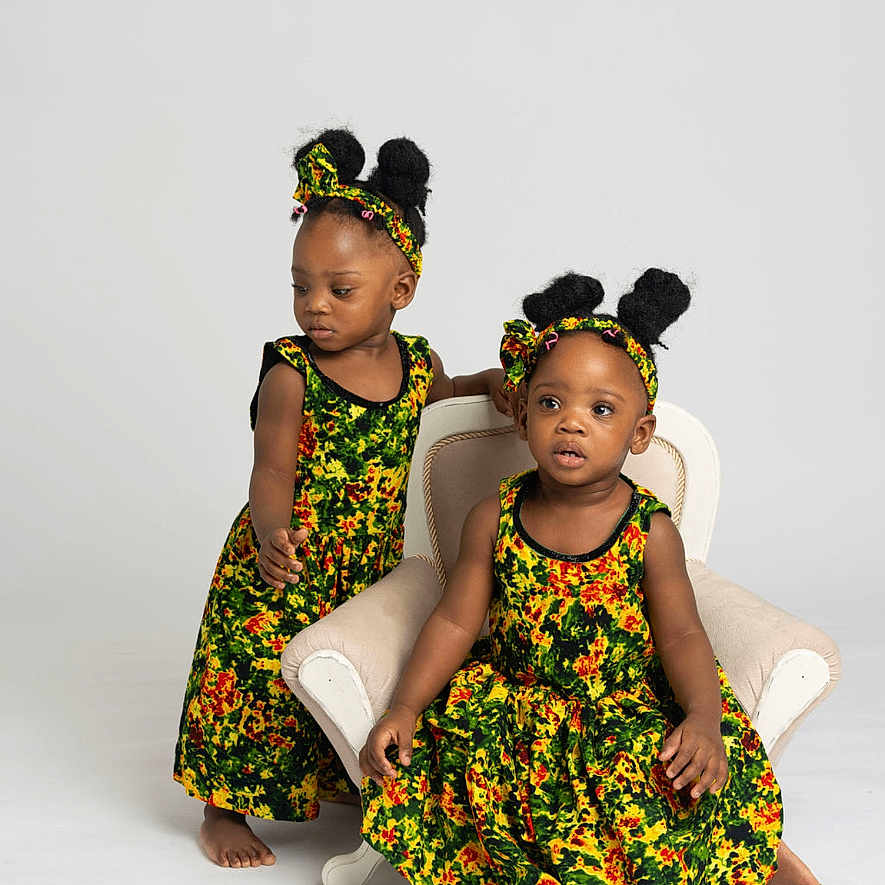 Elizabeth And Esther joined the competition — help win amazing prizes! afro_hairstyle, armchair, barefoot, child, colorful_clothing, cute, dress, fashion, headband, indoor, matching_outfits, photography, portrait, sitting, standing, studio, toddler, two_children, white_background, young_girls