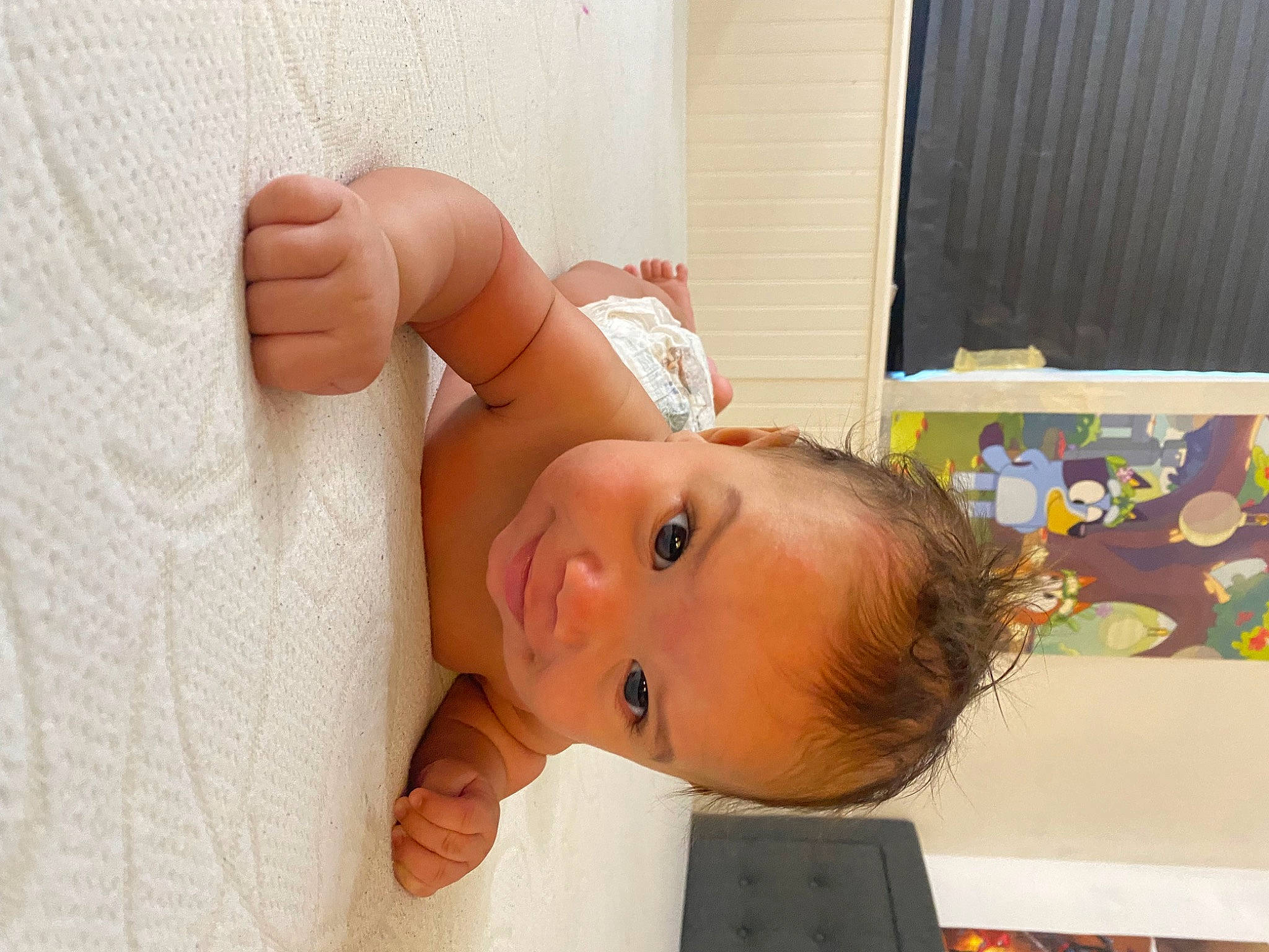 Kenzo is registered to the contest to win money with this photo: abdomen, baby, cheek, chest, child, comfort, elbow, eyebrow, eyelash, flooring, gesture, happy, human_body, nose, person, room, thumb, toddler, trunk, window_blind