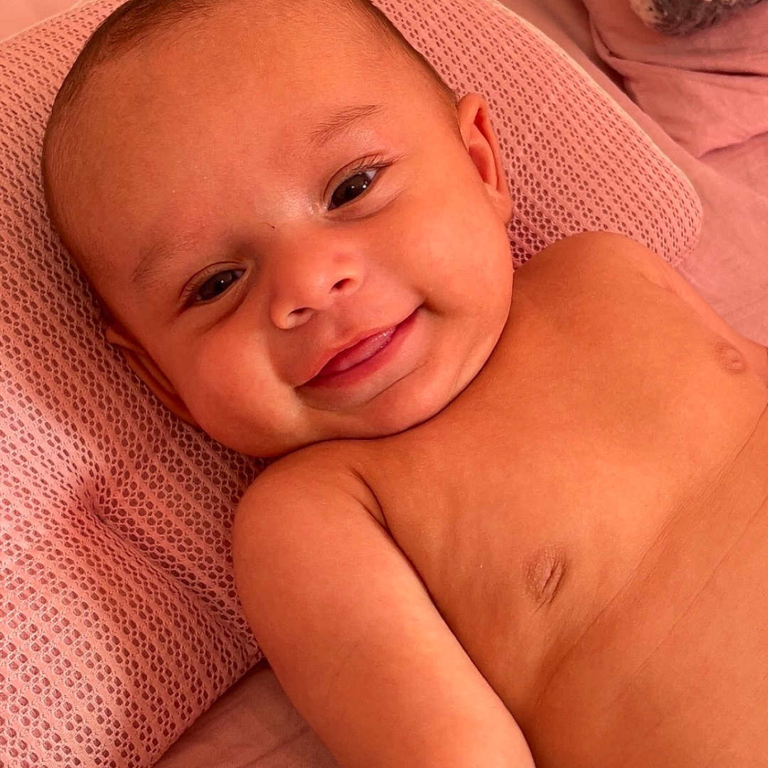 Damian is registered to the contest to win money with this photo: baby, bed, blanket, cheerful, child, closeup, cute, expression, face, happy, head, indoors, infant, lying_down, person, pillow, relaxing, skin, smiling, young