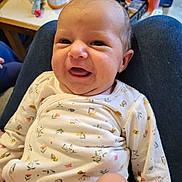 Adriana participe au concours pour gagner de l'argent avec cette photo : baby, background, bottle, candid, casual, clothing, face, floral_pattern, furniture, happy, head, human, indoor, infant, lap, onesie, person, skin, smiling, table