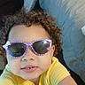 toddler, child, curly_hair, sunglasses, yellow_shirt, flowers, indoor, bedroom, bed, furniture, person, portrait, cute, smiling, selfie, young_child, tiles, casual, happy, playful