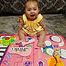 Miracle joined the competition — help win amazing prizes! baby, child, colorful, cute, expression, floor, frog_toy, fun, happy, indoor, infant, maracas, microphone, music_toys, person, play_mat, sitting, smiling, toy, yellow_dress