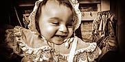 Alessia Reign joined the competition — help win amazing prizes! baby, child, smiling, lace, bonnet, dress, sepia, portrait, indoors, happy, face, clothing, infant, cute, vintage_style, wooden_background, fabric, person, closeup, joy