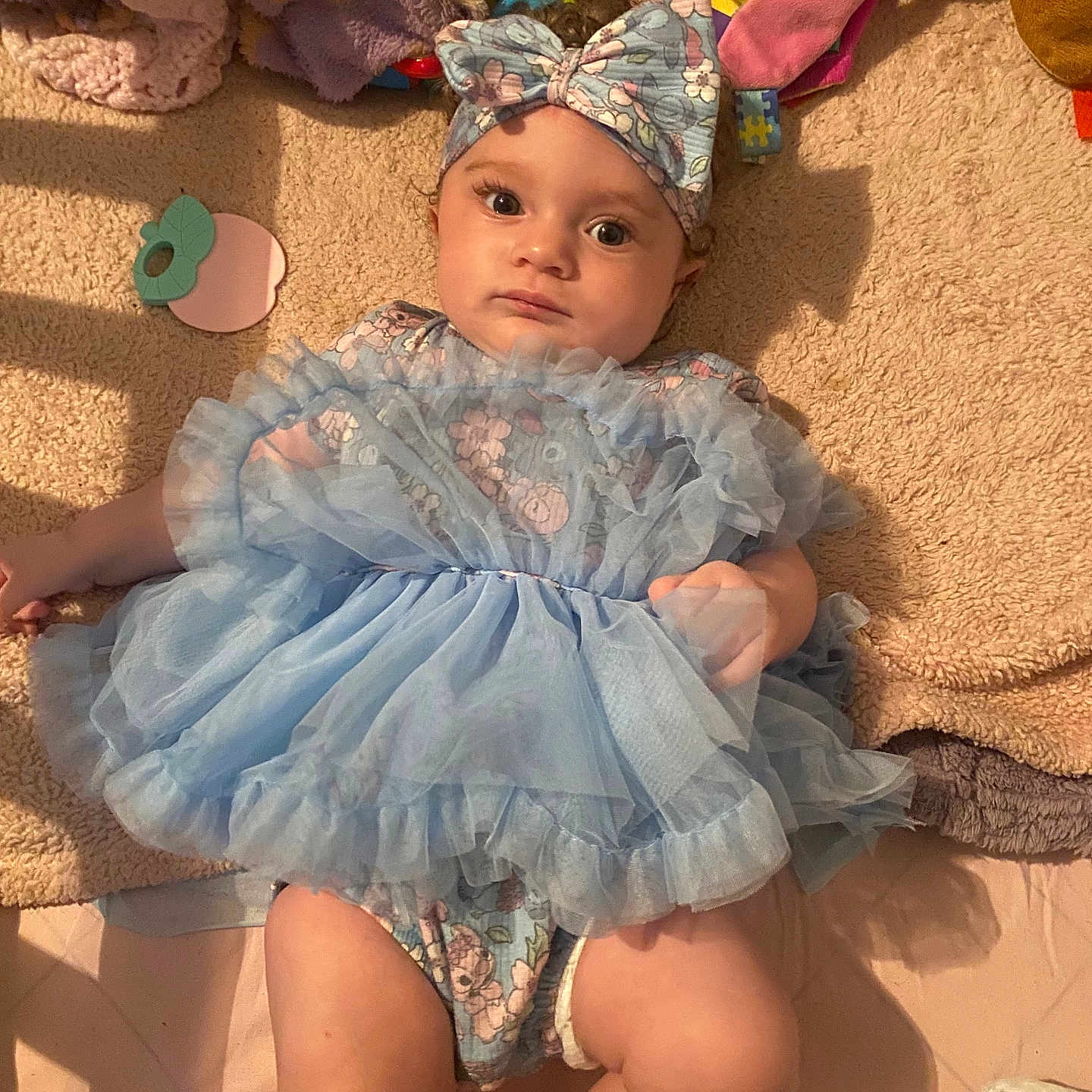 Wynter is registered to the contest to win money with this photo: baby, blanket, blue_dress, child, cloth, cozy, curious_expression, cute, fabric, headband, indoors, infant, lying_down, person, plush, portrait, resting, soft_toys, toddler, wearing