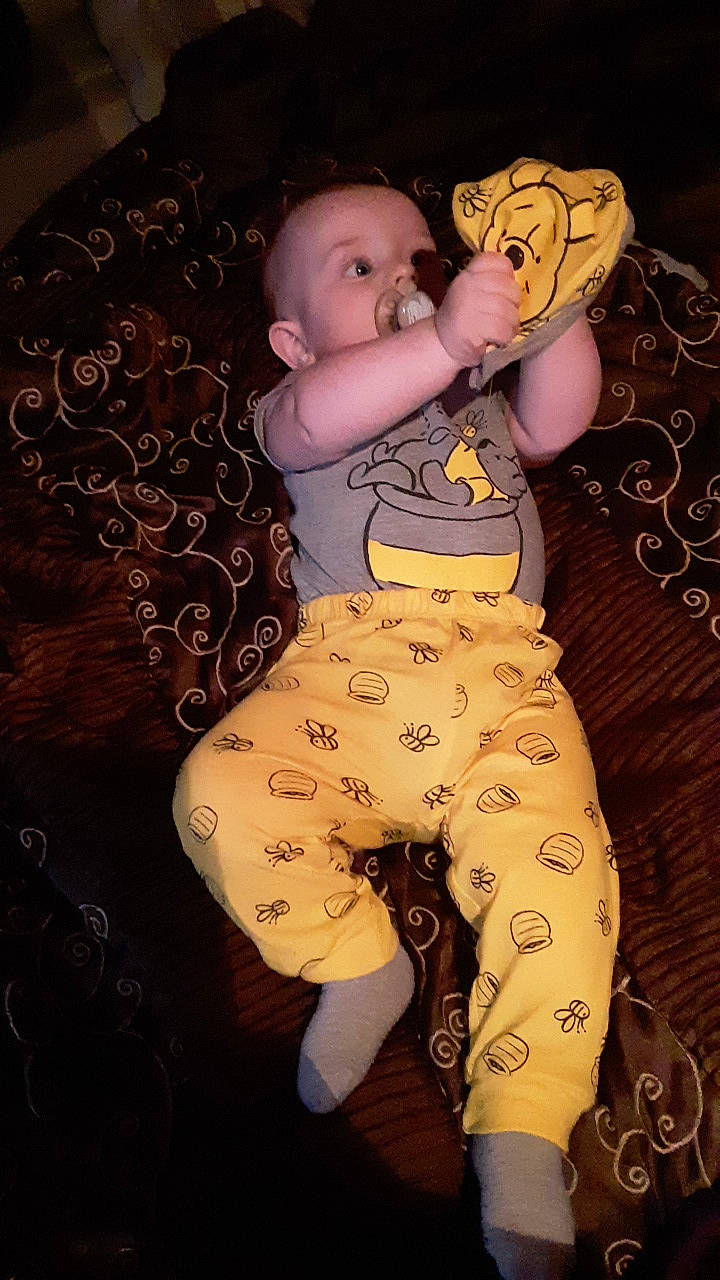 Liam is registered to the contest to win money with this photo: abdomen, active_pants, arm, baby, chest, comfort, eye, hand, happy, head, human_body, knee, person, stomach, textile, thigh, thumb, toy, trunk, waist